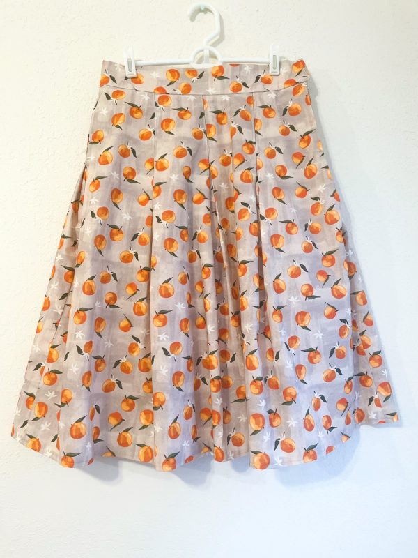 Spring Oranges Skirt -skirt with gray background and oranges pattern. Has pockets, and pleats. Fitted waistband. Zips closed at the left side