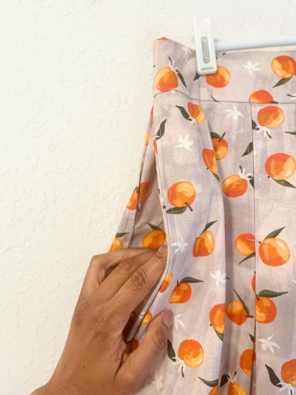 Up close photo of the pocket on the Spring Oranges Skirt -skirt with gray background and oranges pattern. Has pockets, and pleats. Fitted waistband. Zips closed at the left side