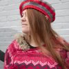 girl standing against a gray wall wearing a scarlet and gray tam with a grey pom pom
