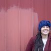 girl wearing a navy blue handmade crocheted headband or ear warmer. The ear warmer has a hand crocheted flower with a brown button center