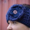 girl wearing a navy blue handmade crocheted headband or ear warmer. The ear warmer has a hand crocheted flower with a brown button center