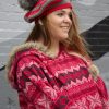 girl standing against a gray wall wearing a scarlet and gray tam with a grey pom pom