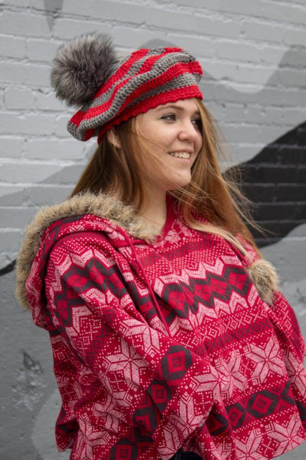 girl standing against a gray wall wearing a scarlet and gray tam with a grey pom pom