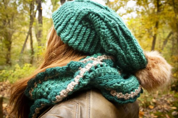 Girl outside wearing a vibrant green floppy toboggan and infinity scarf matching set. The toboggan and scarf are handmade by MiasWorkshop. The hat is hand knit. The scarf is crocheted. The toboggan has a tan pom pom attached. The scarf has a matching tan stripe running through it.