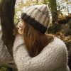 girl wearing a fuzzy cream and dark brown hand crocheted beanie with three coconut buttons sewn on the side