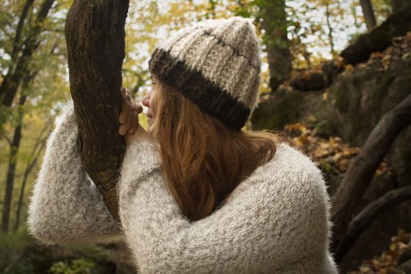 girl wearing a fuzzy cream and dark brown hand crocheted beanie with three coconut buttons sewn on the side