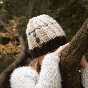 girl wearing a fuzzy cream and dark brown hand crocheted beanie with three coconut buttons sewn on the side