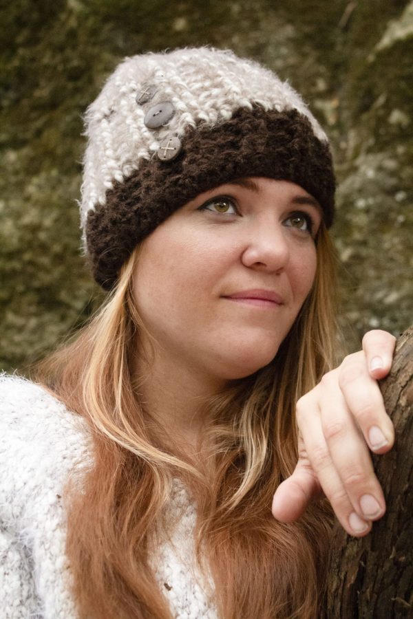 girl wearing a fuzzy cream and dark brown hand crocheted beanie with three coconut buttons on the side