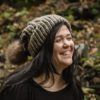 girl wearing taupe hand knit toboggan with tan pom pom