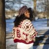 a girl standing outside in a pink, dark red, dark brown, and cream granny square sweater. The sweater buttons up the front. MiasWorkshop
