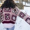 a girl standing outside in a pink, dark red, dark brown, and cream granny square sweater. The sweater buttons up the front. MiasWorkshop