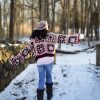 a girl standing outside in a pink, dark red, dark brown, and cream granny square sweater. The sweater buttons up the front. MiasWorkshop
