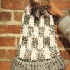 girl holding a handmade, knit, slouchy, fuzzy, cream and gray checkered toboggan with a gray pom pom attached