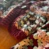 A pink and dark red granny square sweater laying on a table with a button closure